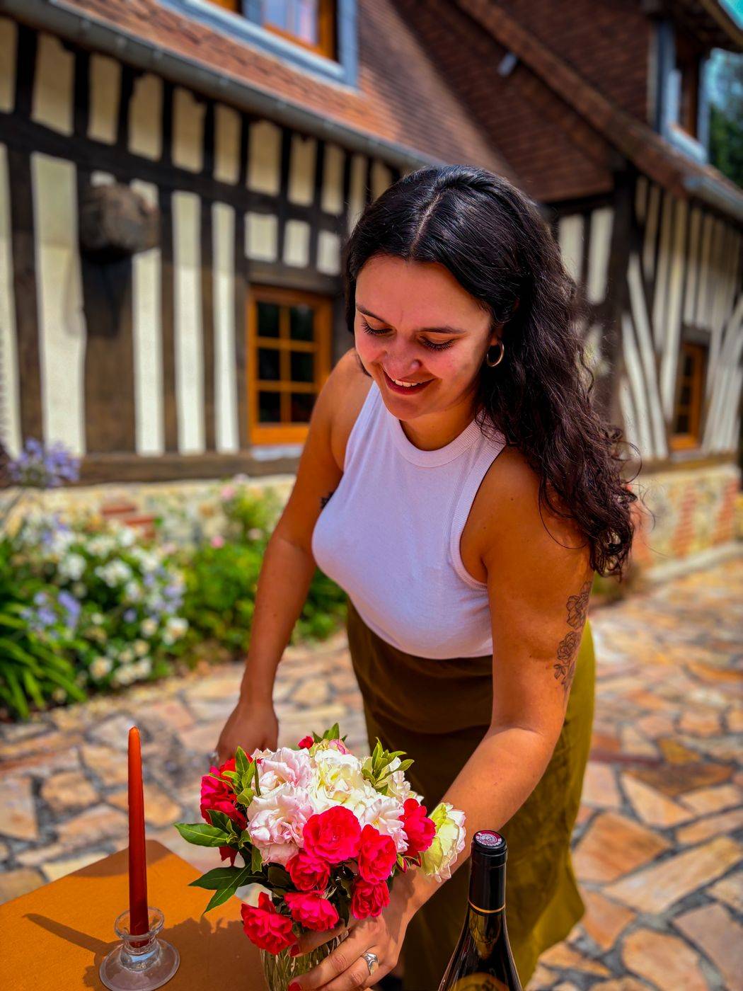 Caroline souriante, en train de dresser une table de mariage avec un bouquet de roses