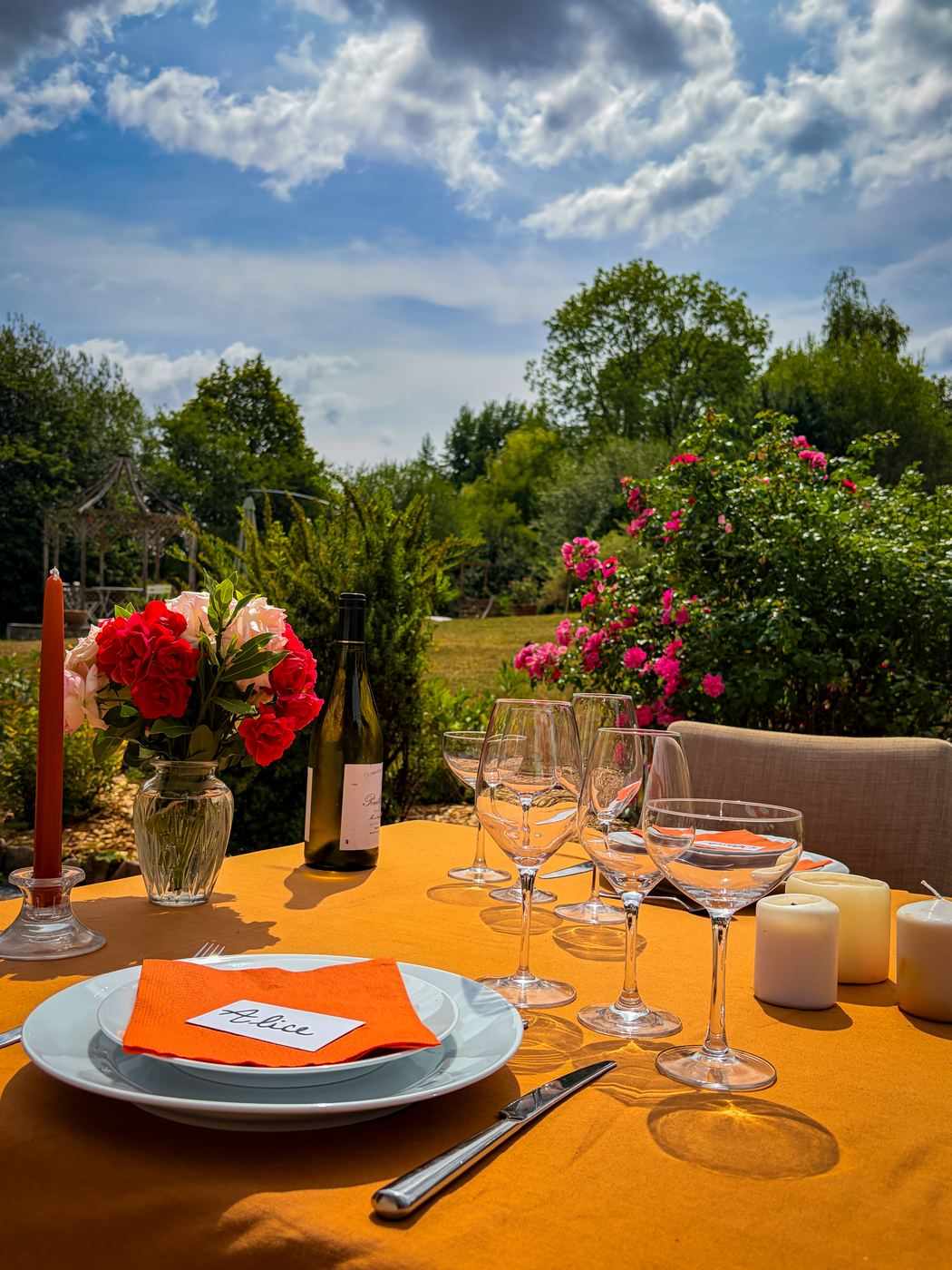 Table de mariage dressée avec vaisselle, verres et bougies dans une lumière chaude de fin de journée