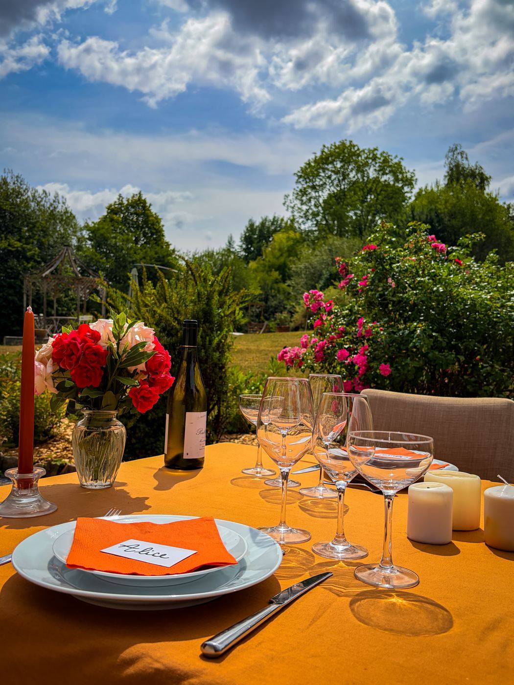 Table de mariage dressée avec vaisselle, verres et bougies dans une lumière chaude de fin de journée